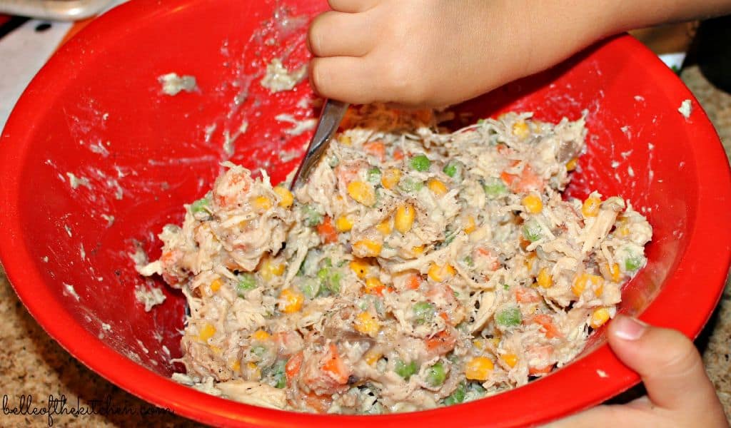 A person stirring chicken pot pie filling