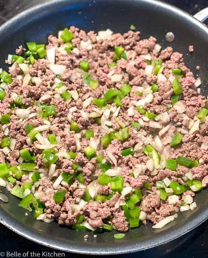 black skillet with ground beef, chopped onions, and green peppers