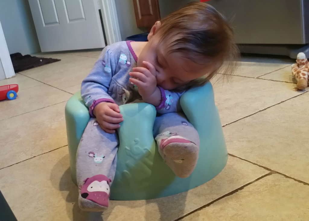 A little girl sitting on a bumbo