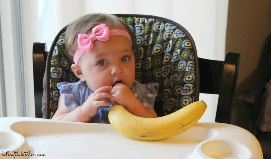 A little girl holding a banana 