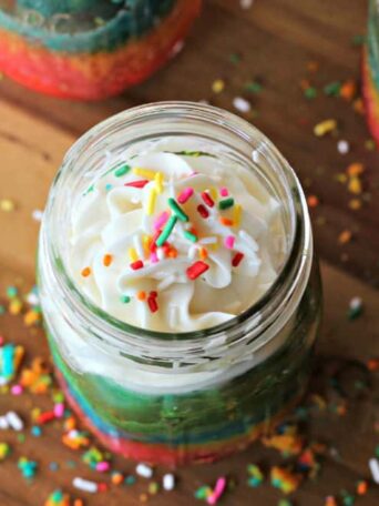 cake in a jar with frosting on top and sprinkles