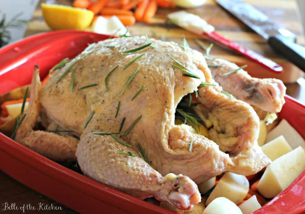 a raw whole chicken with rosemary on top