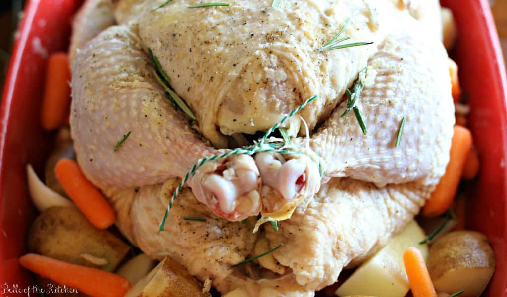 a raw whole chicken with trussed legs