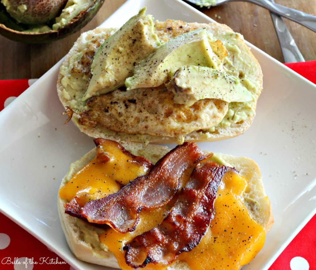 a plate with an open sandwich of bacon, cheese, avocado, and egg