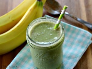 a green smoothie with bananas in the background