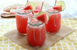 three cups filled with watermelon lemonade, topped with chopped watermelon and lemon slices