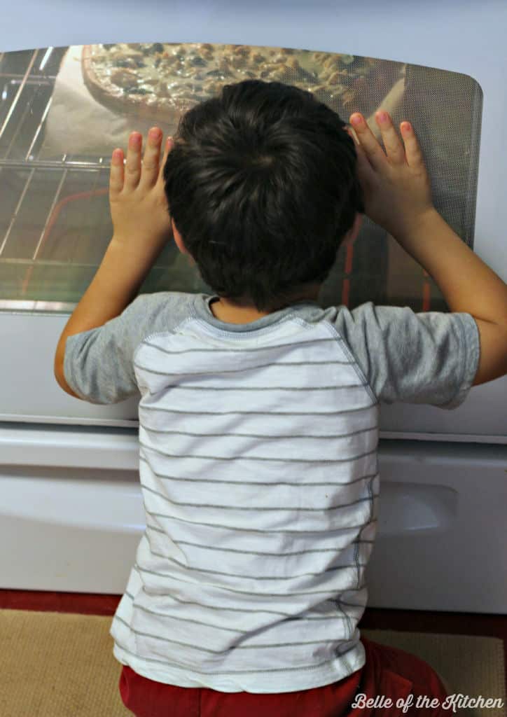 A little boy looking in the oven