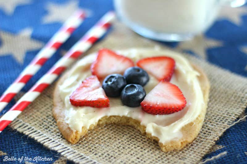 A close up of a cookie with fruit on top and a bite taken out