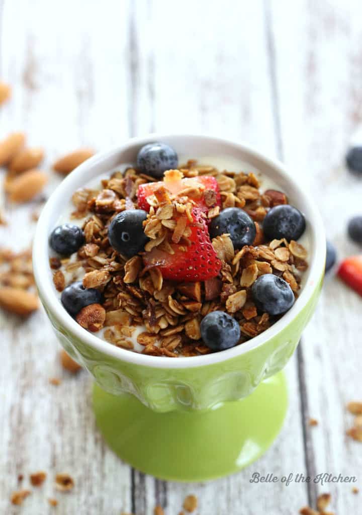 A close up of a bowl of granola with fruit in the background
