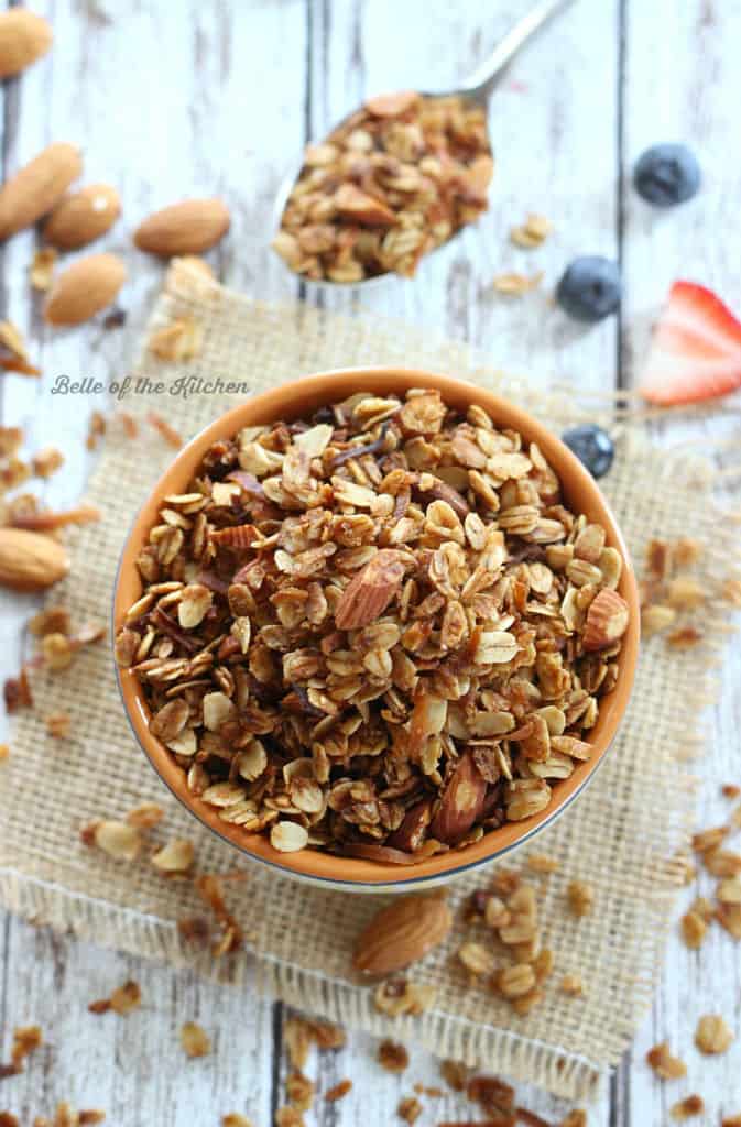 A close up of a bowl of granola with fruit in the background