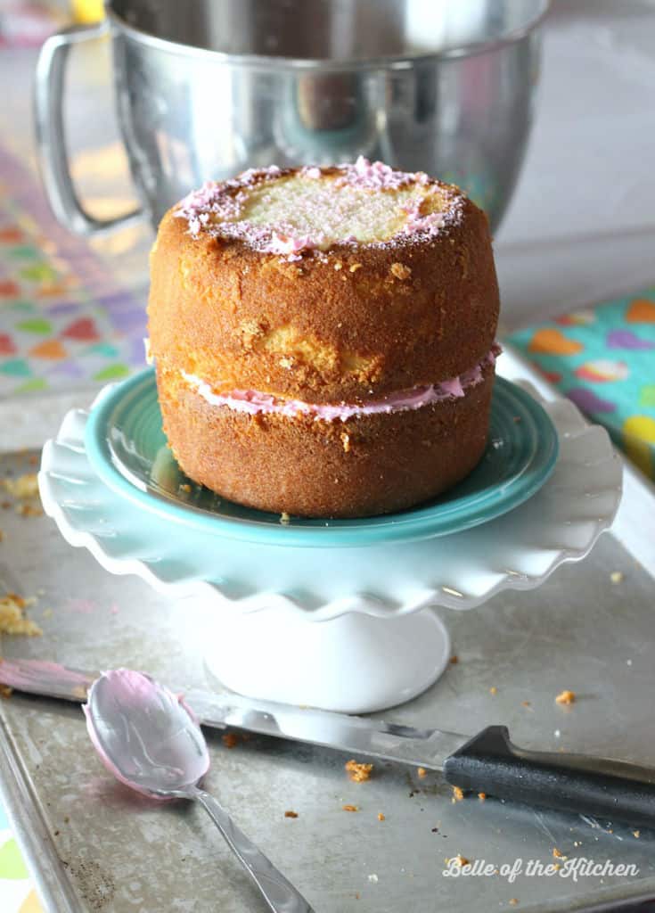 A cake sitting on a cake stand ready to be frosted