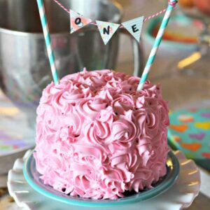 A plate with a pink frosted birthday cake