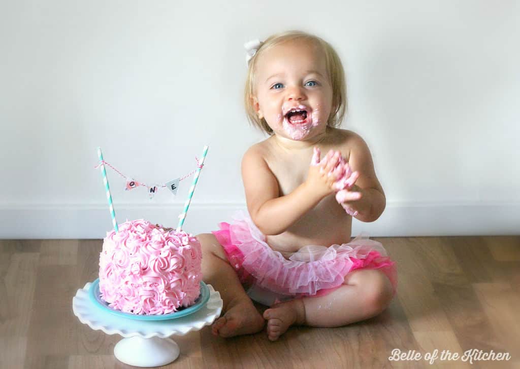 A little girl next to a pink cake