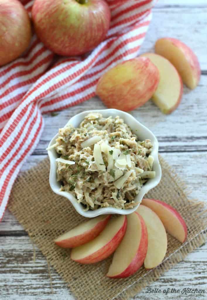 a white bowl with tuna salad and sliced apples