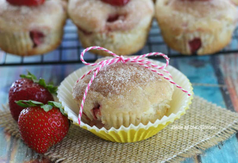 a muffin with strawberries beside it, wrapped in string