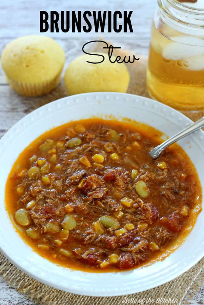 A bowl of stew with cornbread and iced tea beside it