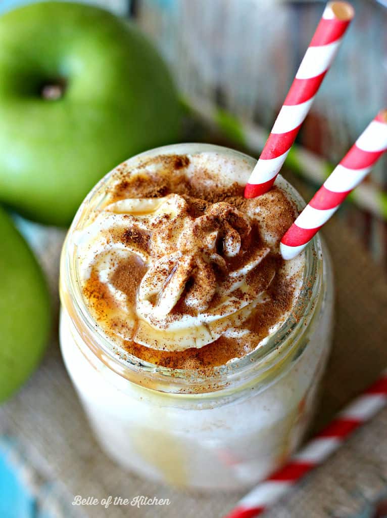 a milkshake beside green apples