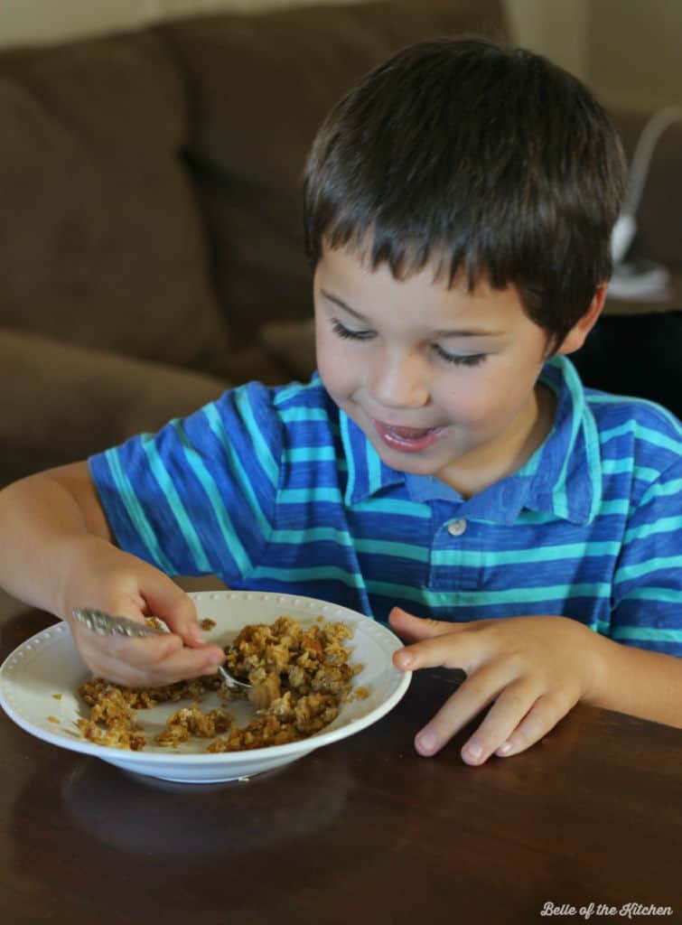 A young boy sitting at a table eating food

