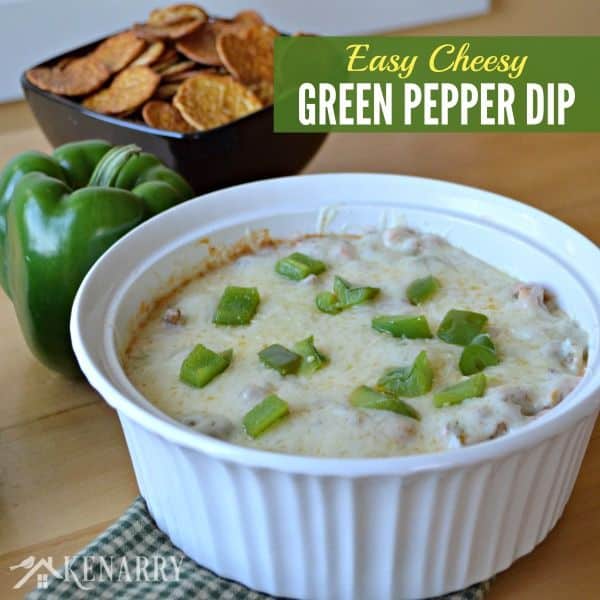 A bowl of green pepper dip on a table with a bowl of chips beside it