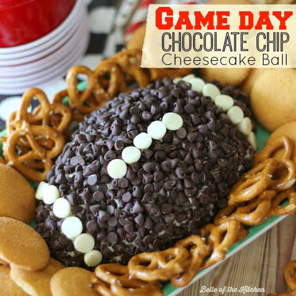 A cheeseball shaped like a football topped with chocolate chips and surrounded by pretzels and vanilla wafers