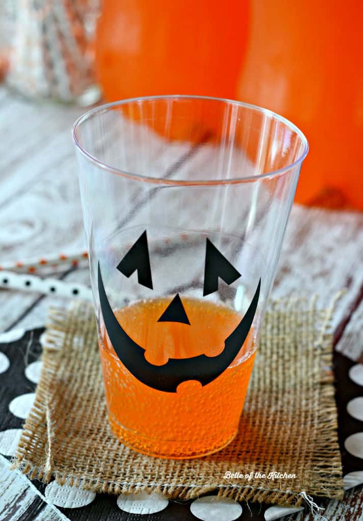 A close up of a glass with a jack o\'lantern face on the side