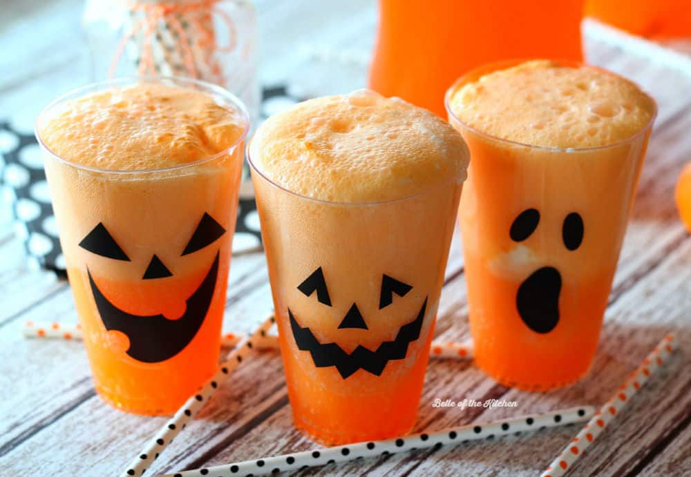 cups filled with Fanta, vanilla ice cream, and jack o\'lantern faces on the side of the cups