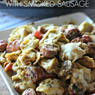 Tortellini with smoked sausage drenched in a creamy pesto Alfredo sauce with tomatoes, garlic, and gooey cheese. It's the perfect easy and delicious dinner!
