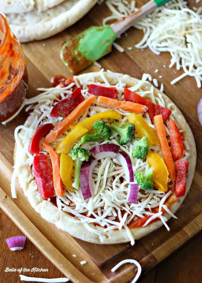 A plate with a pizza and toppings in the shape of a rainbow