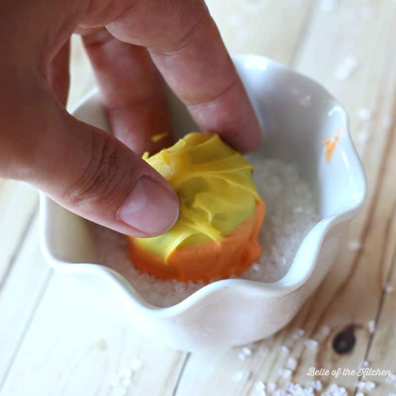 a hand dipping a cake ball in sprinkles