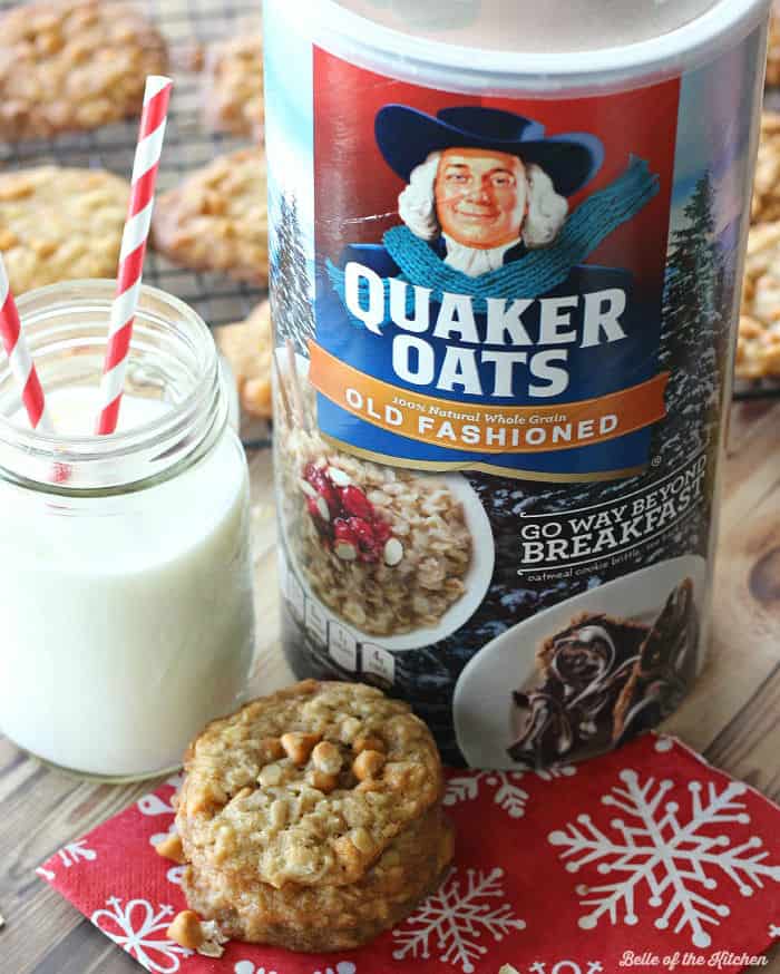 A close up of a stack of oatmeal cookies next to a glass of milk and a package of oatmeal