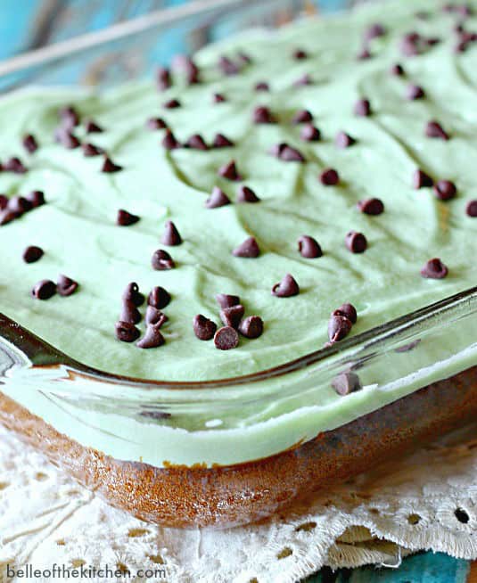 A close up of a baking dish of chocolate brownies topped with mint frosting and chocolate chips