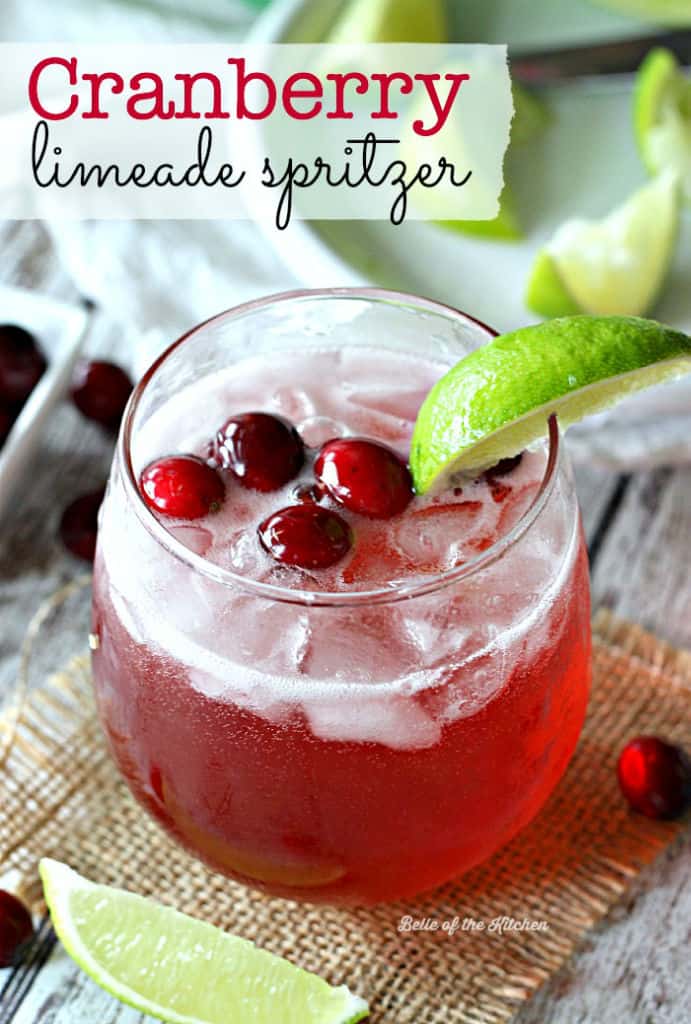 A glass of limeade with cranberries and a lime slice