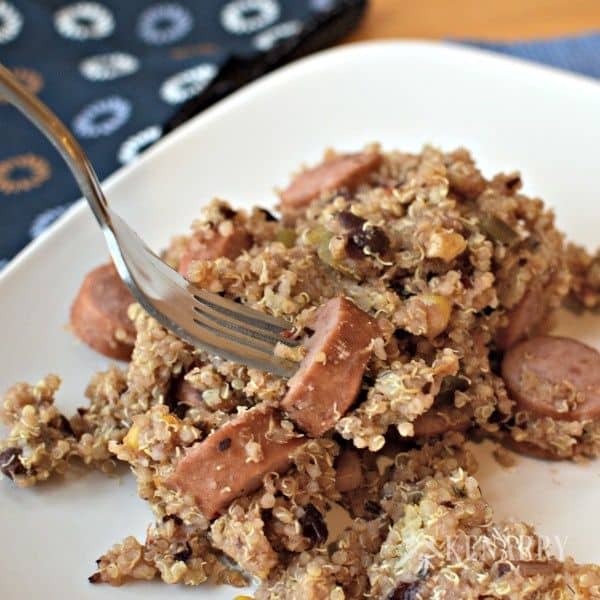 A plate of food filled with sausage and quinoa with a fork
