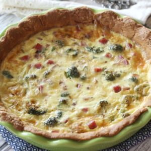 a green pie plate filled with broccoli quiche