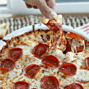 a chip being dipped into pepperoni pizza dip