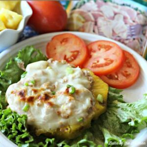 a tuna melt on top of a pineapple with tomatoes and lettuce