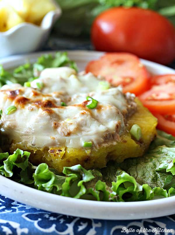 a tuna melt on top of a pineapple with tomatoes and lettuce