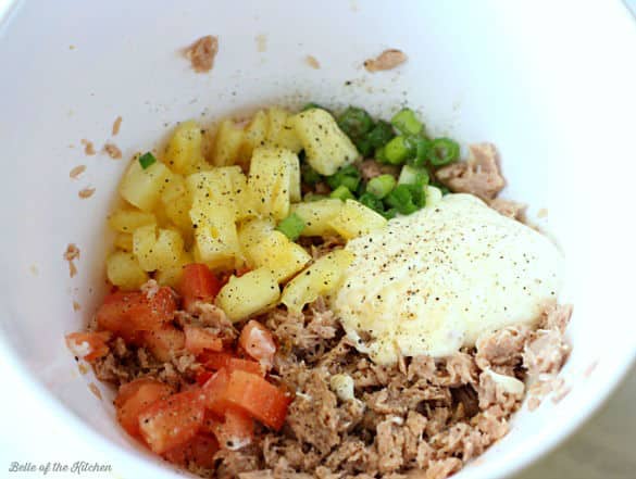 A bowl of tuna salad mixed with pineapple, tomatoes, green onions, and mayo