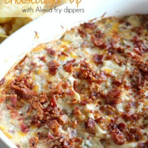 A dish filled with cheeseburger dip topped with bacon