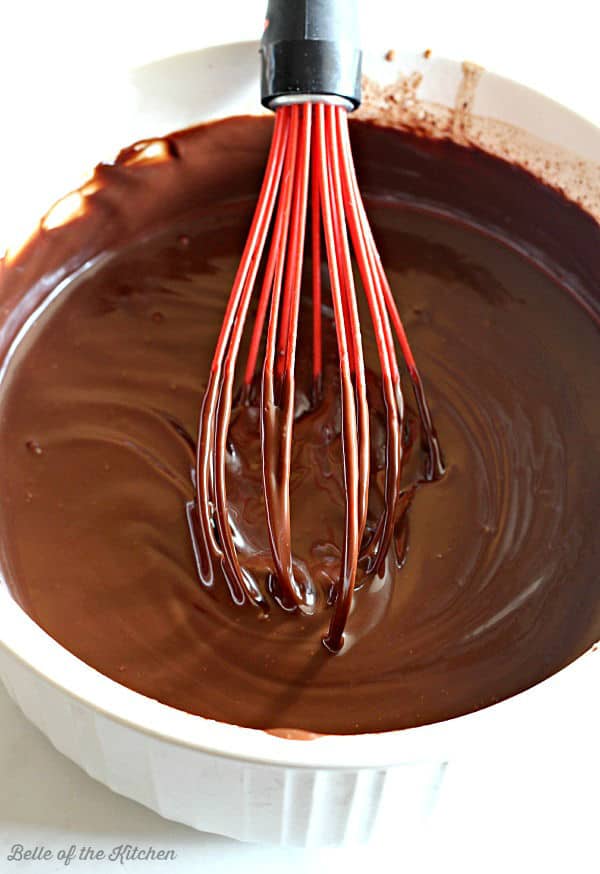 a bowl of chocolate ganache with a red whisk