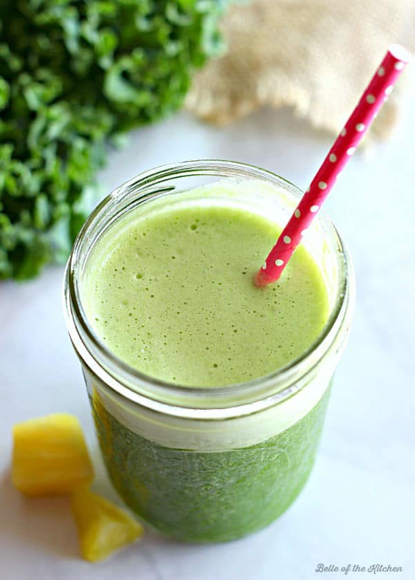 A mason jar filled with a green smoothie and a pink straw