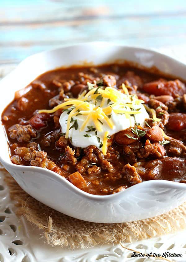 A bowl of chili topped with sour cream and shredded cheese