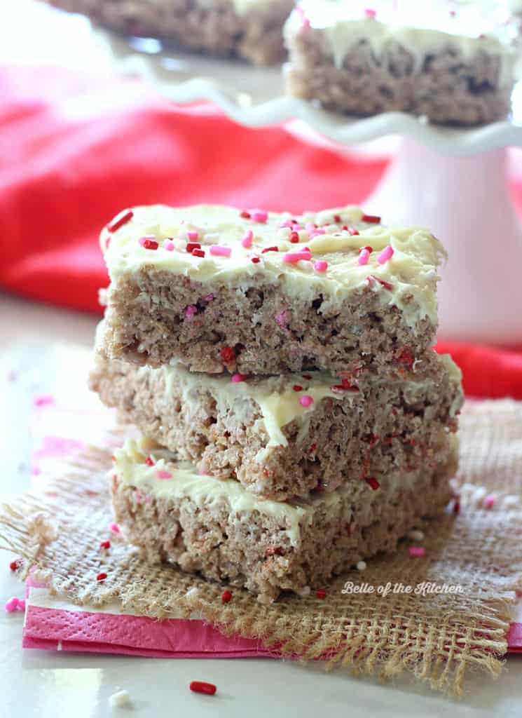 a stack of Rice Krispie treats topped with frosting and pink sprinkles