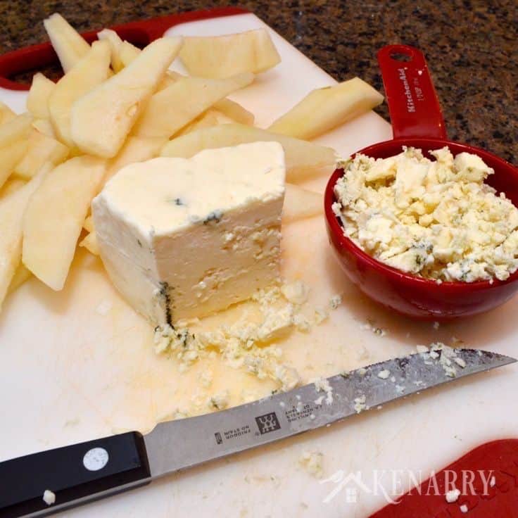 a cutting board with sliced pears, cheese, and a knife