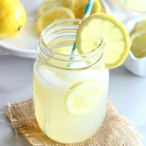 a glass of lemonade with a straw and lemon slice on the side