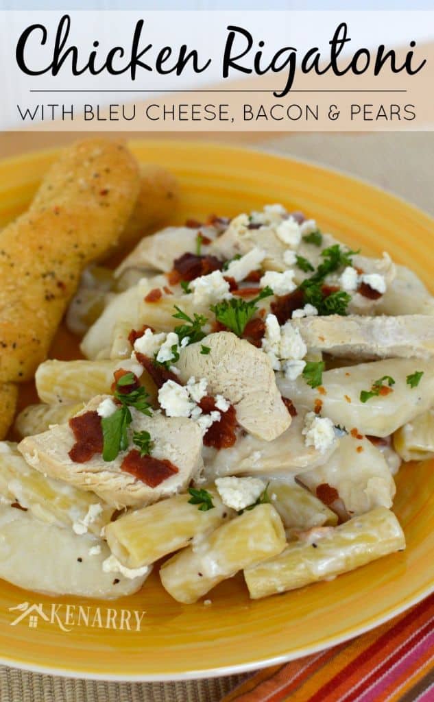 A plate of pasta with chicken and bread sticks on the side