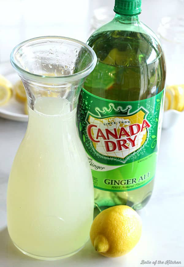 a carafe full of lemonade next to a bottle of ginger ale