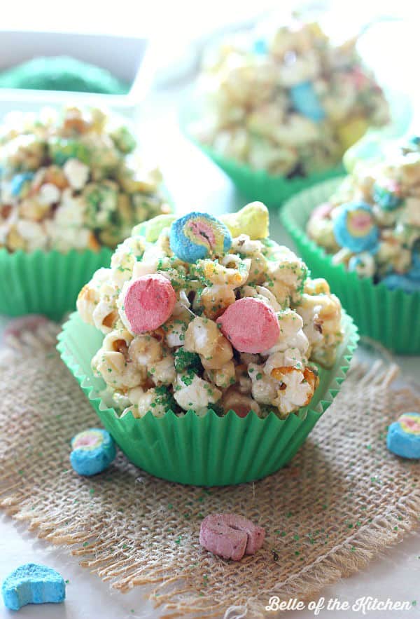 popcorn balls in green paper muffin cups topped with lucky charms marshmallows