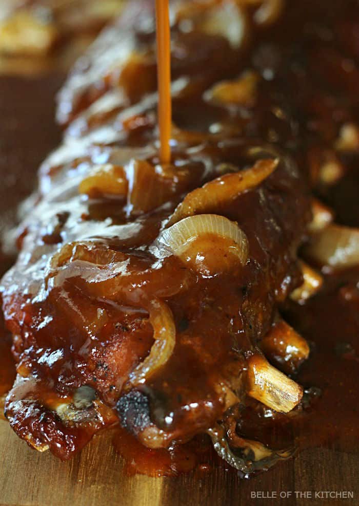 A close up of ribs being poured with sauce