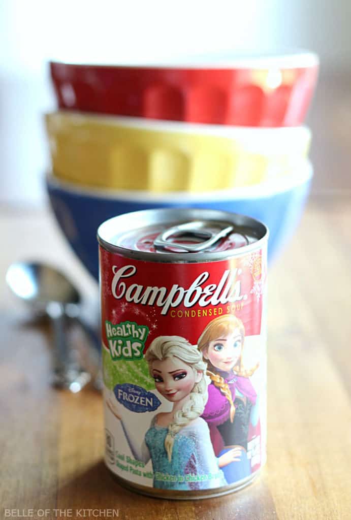 a can of soup beside a stack of bowls and spoons
